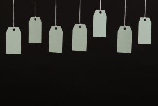 Multiple blank tags hanging on strings against a black background