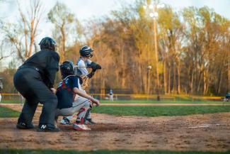 a youth baseball game featuring a batter, catcher, and umpire in action on the field.