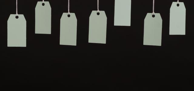 Multiple blank tags hanging on strings against a black background