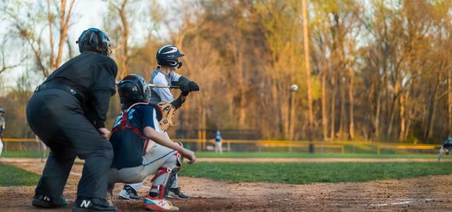 a youth baseball game featuring a batter, catcher, and umpire in action on the field.