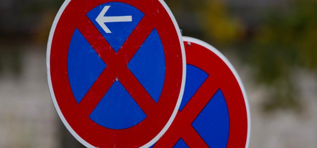 Two red and blue no parking traffic signs outdoors with arrows pointing left and right.