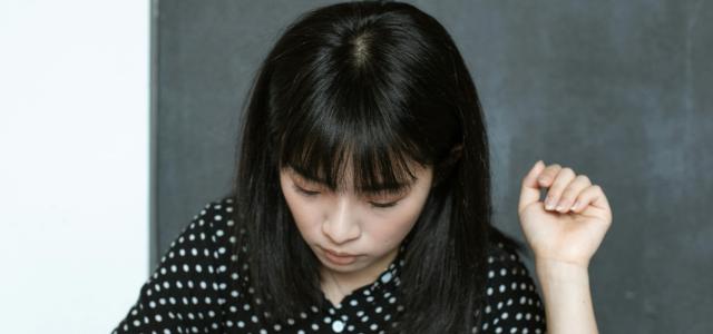 A Woman Wearing a Polka Dot Blouse Using a Calculator
