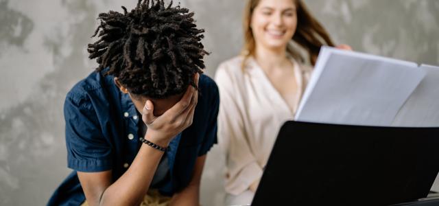Young boy feeling overwhelmed at piano lesson with supportive teacher nearby